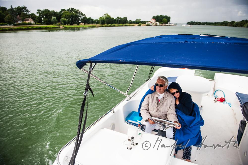seniors in the cockpit of their house boat enjoying the landscape
