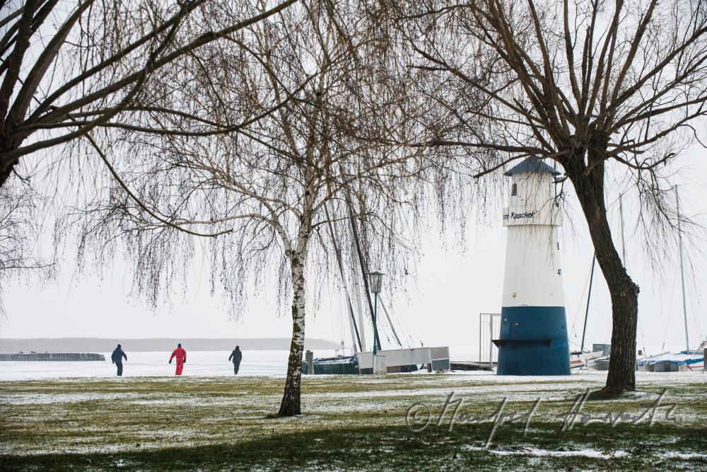 lighthouse and ice-skaters on the lake