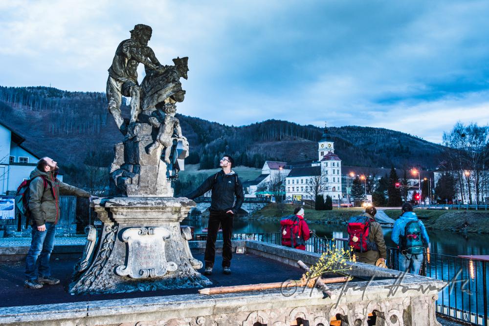 pilgrims rest at the statue of John of Nepomuk