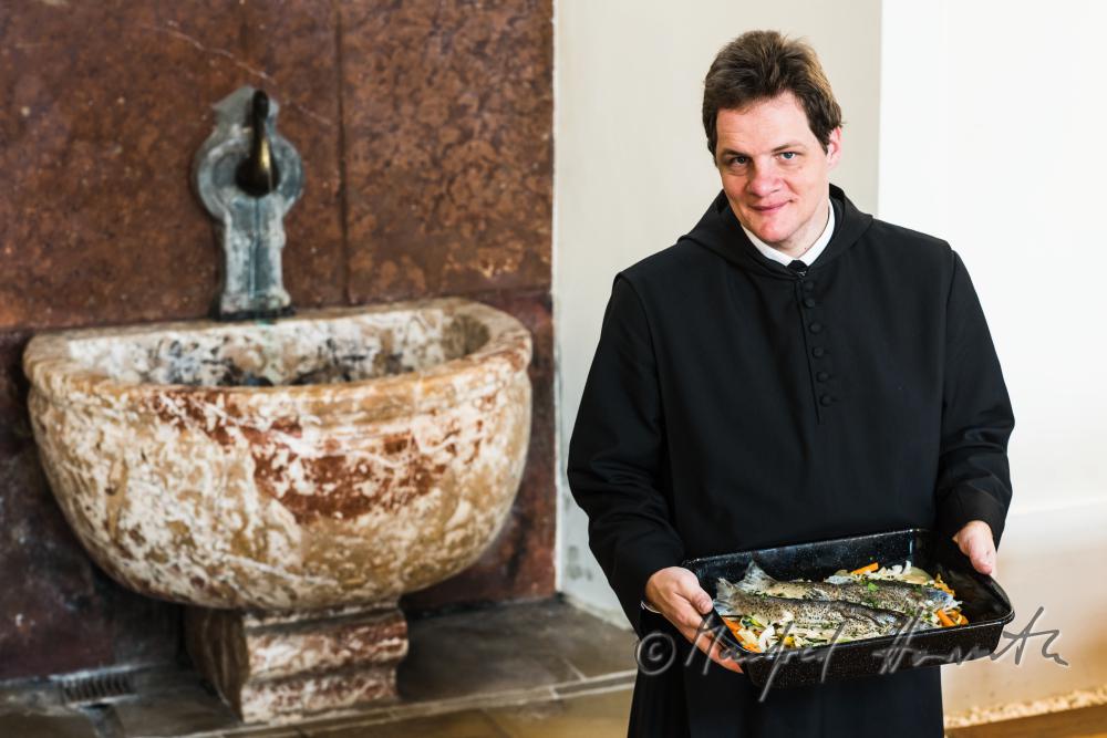 monk in the dining hall with a fish dish