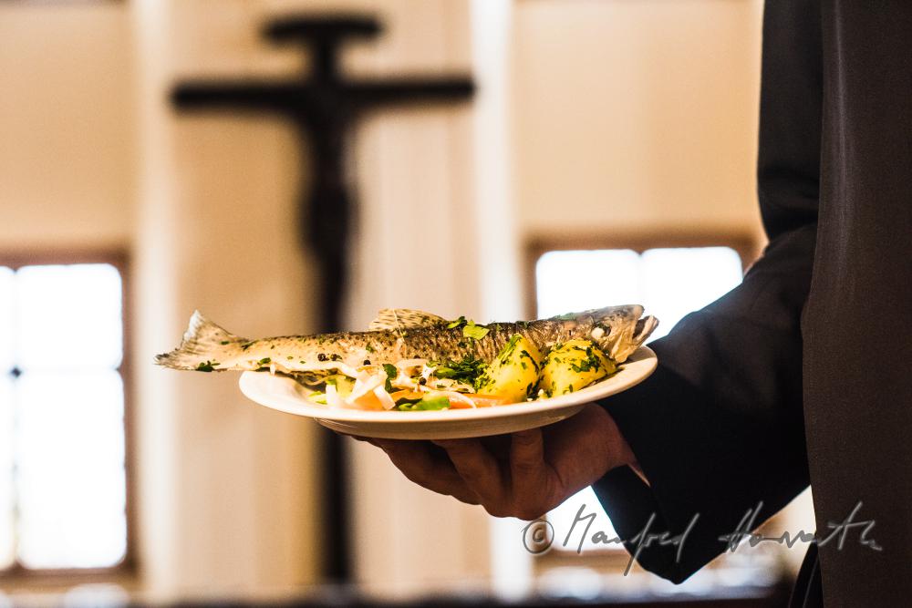 monk in the dining hall with a fish dish