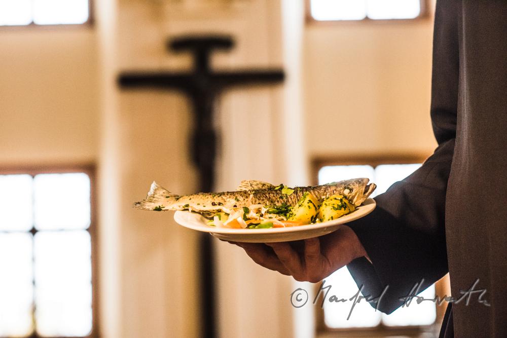 monk in the dining hall with a fish dish