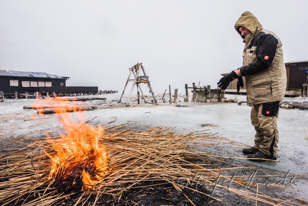 picket-worker warming up on burning reed